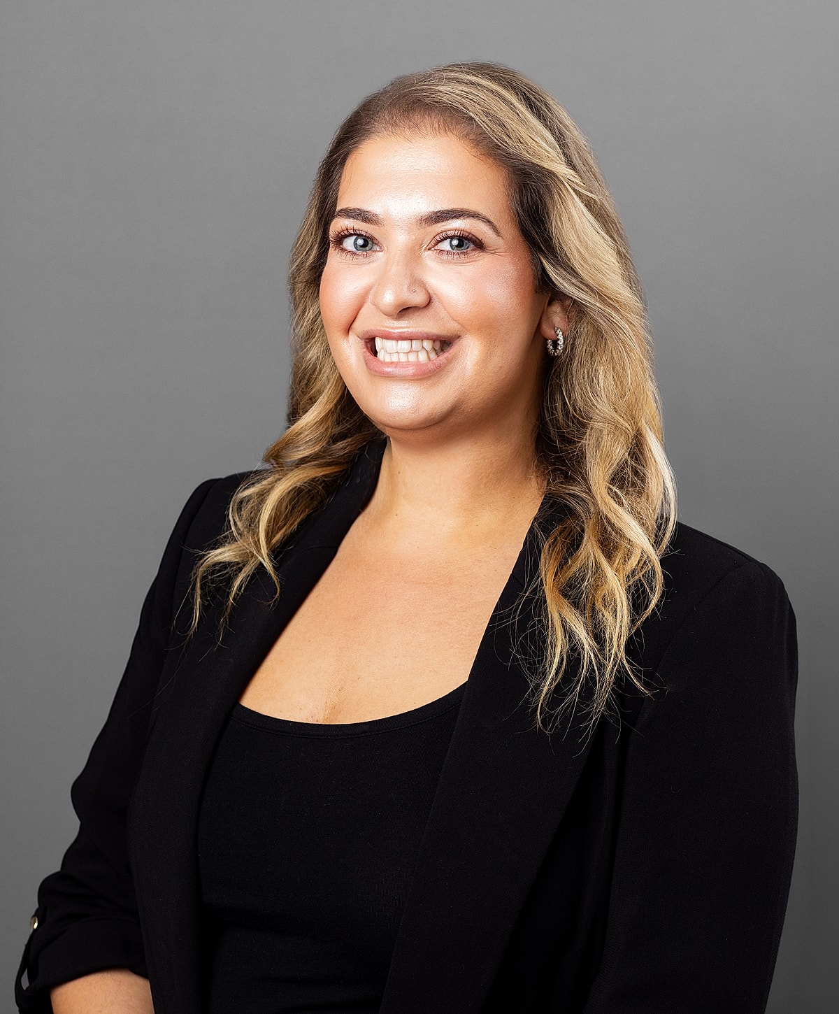 Professional woman smiling against gray background.