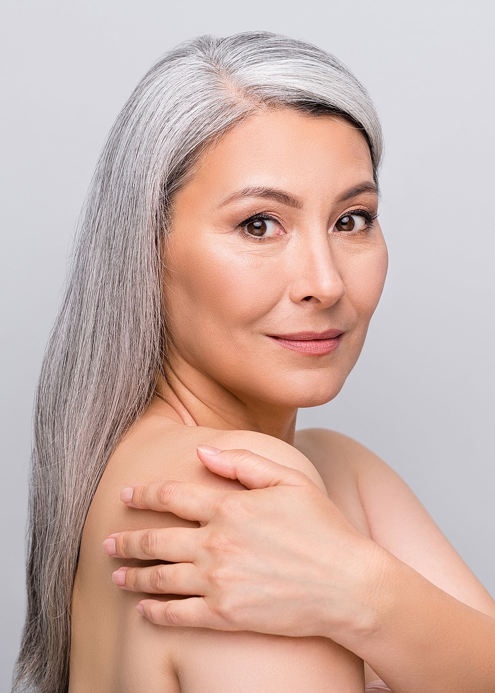 Woman with silver hair, soft expression, light background.