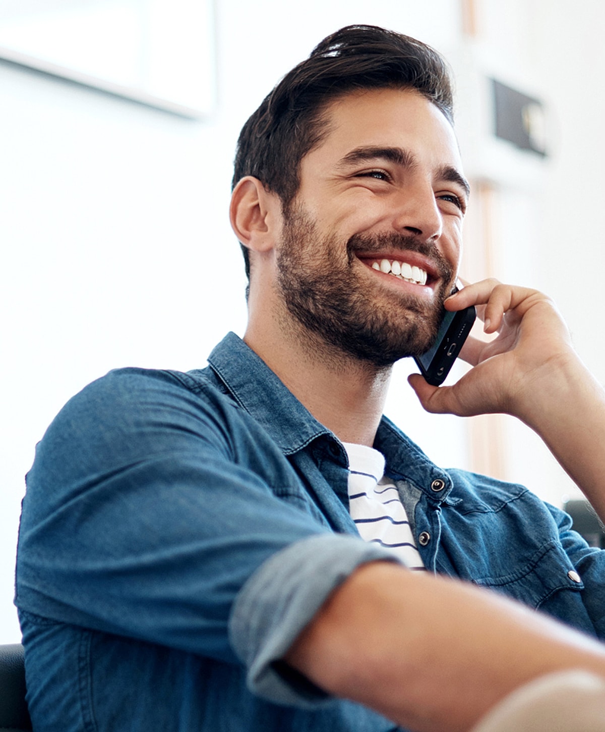 Man smiling while talking on the phone.