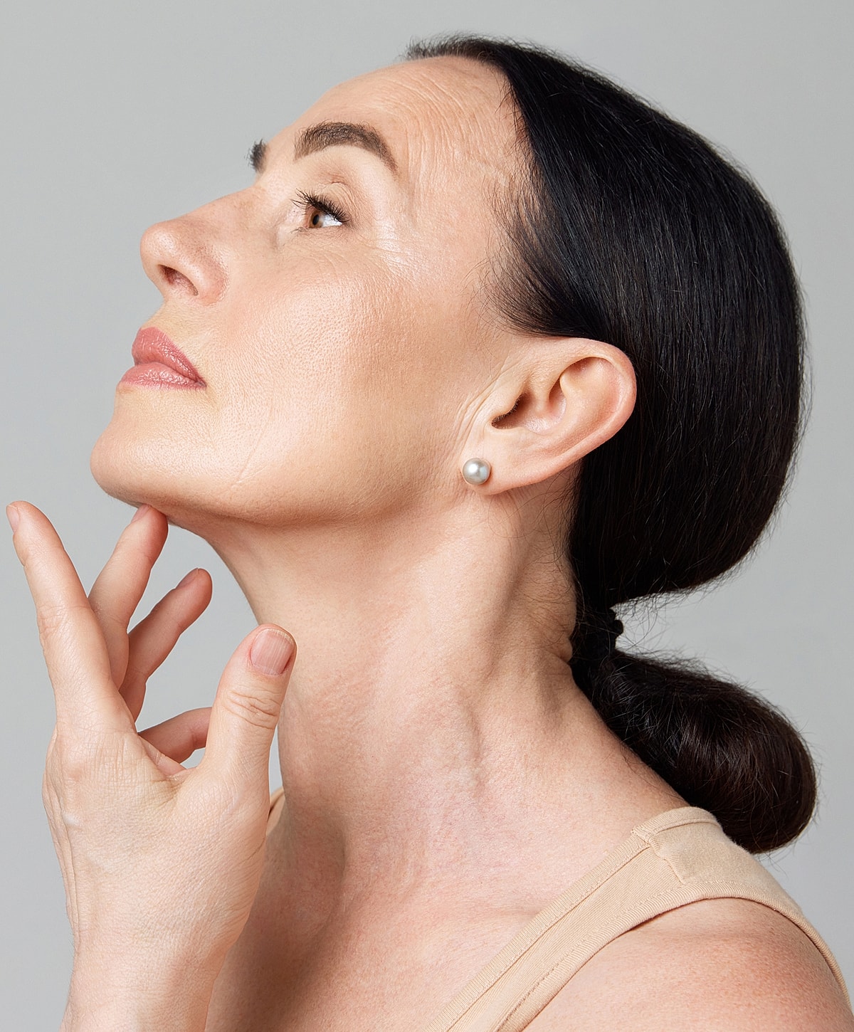 Woman in profile touching her neck gently.