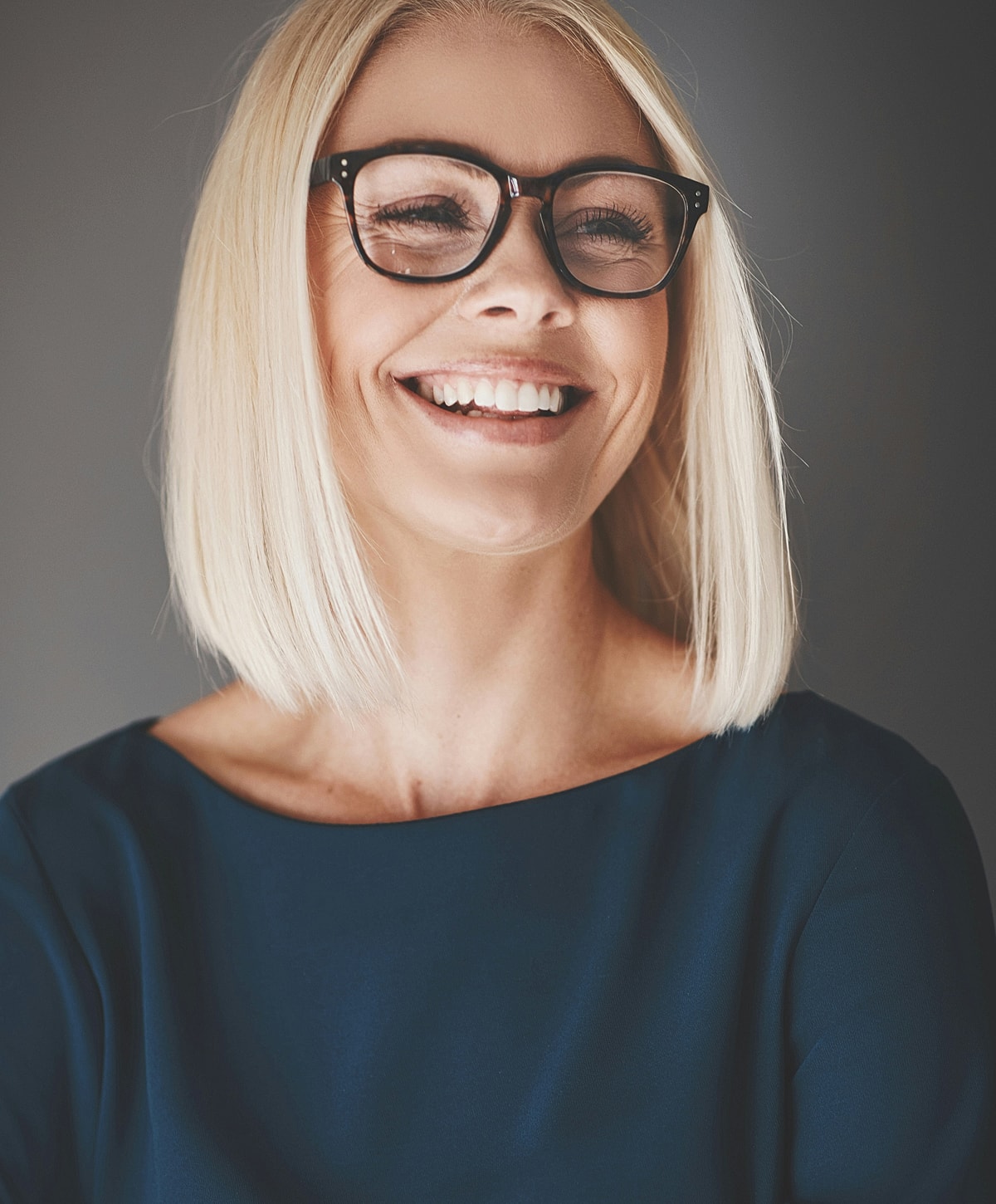 Smiling woman with glasses and blonde hair.