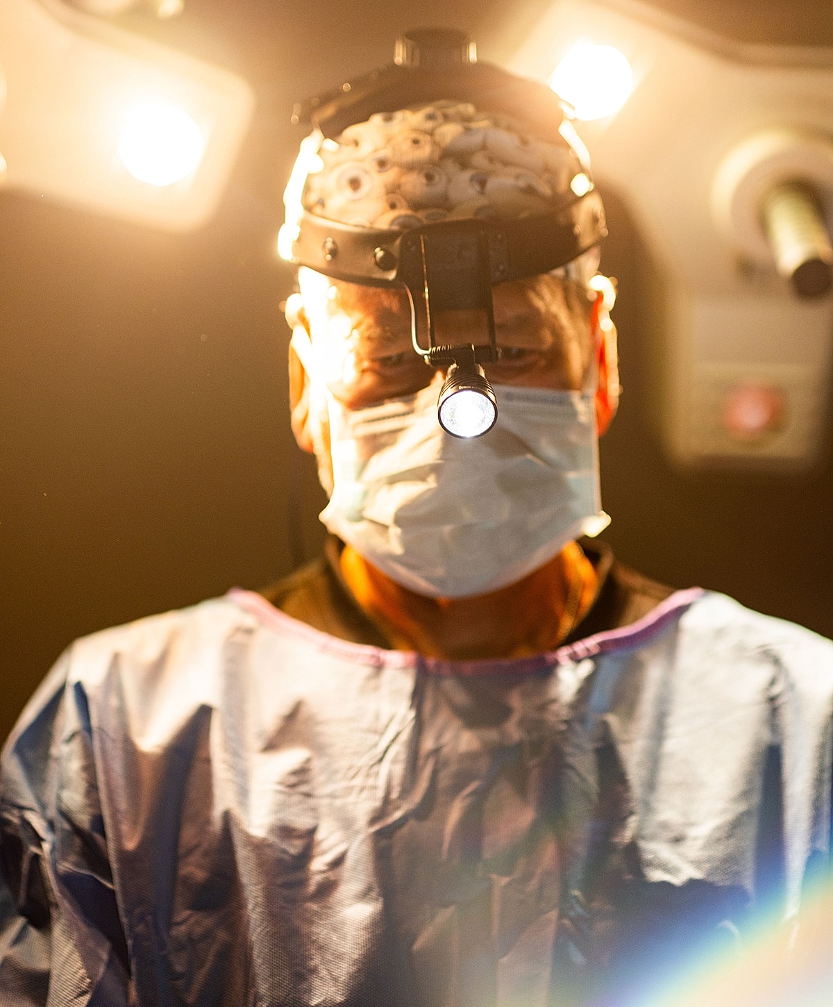 Surgeon in surgical attire with headlamp.
