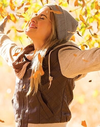 Woman enjoying autumn leaves outdoors.