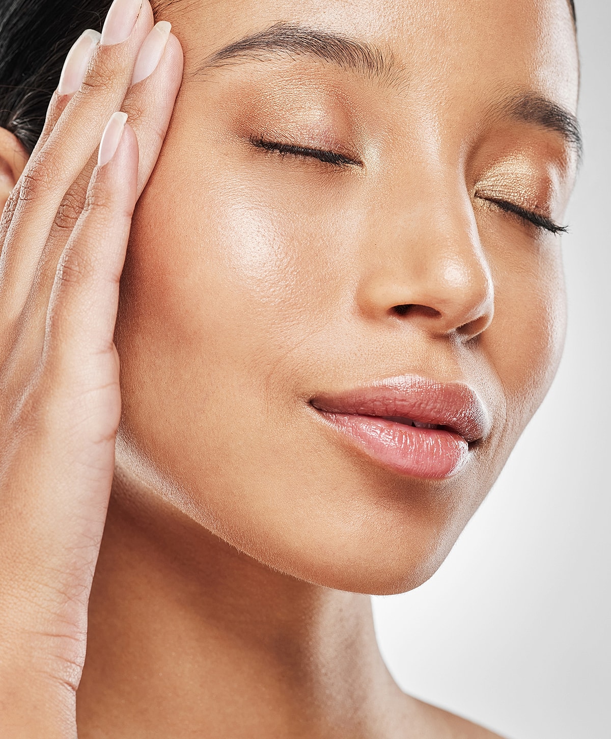Close-up of woman with glowing skin and light makeup.