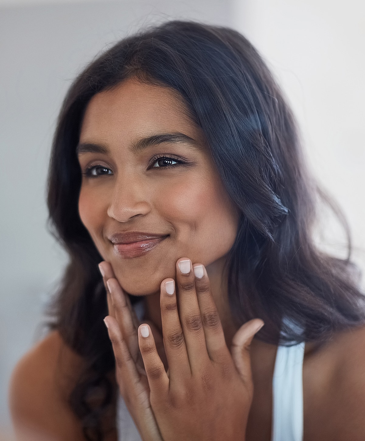 Woman smiling and touching her face gently.
