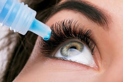 Close up of woman putting eye drops in eye